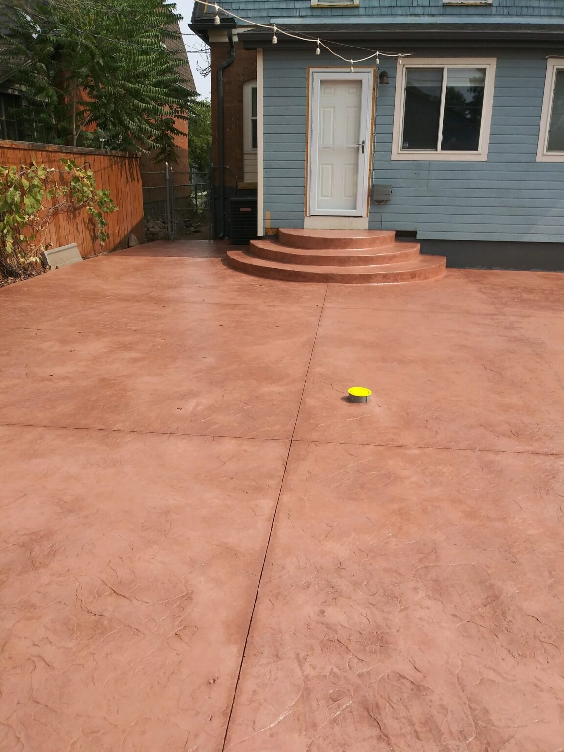 A colored stamped concrete patio with steps leading to a house.